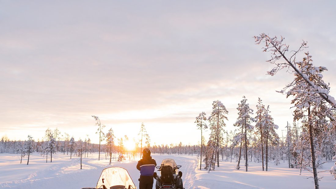 Caravana de motos de nieve al amanecer en plena naturaleza nevada