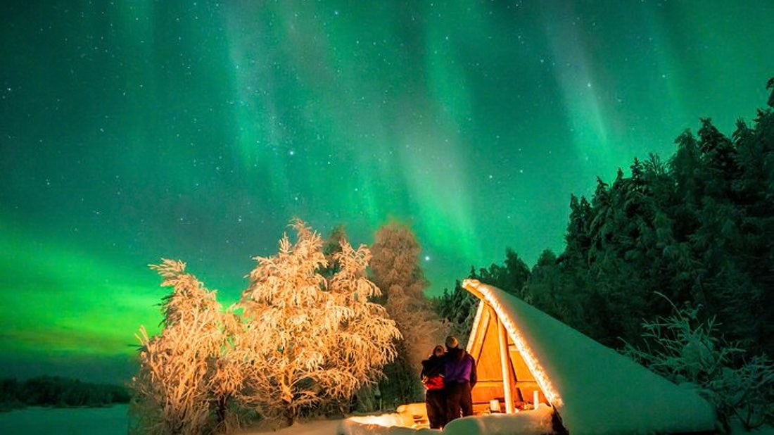 Auroras boreales sobre una cabaña iluminada en el bosque