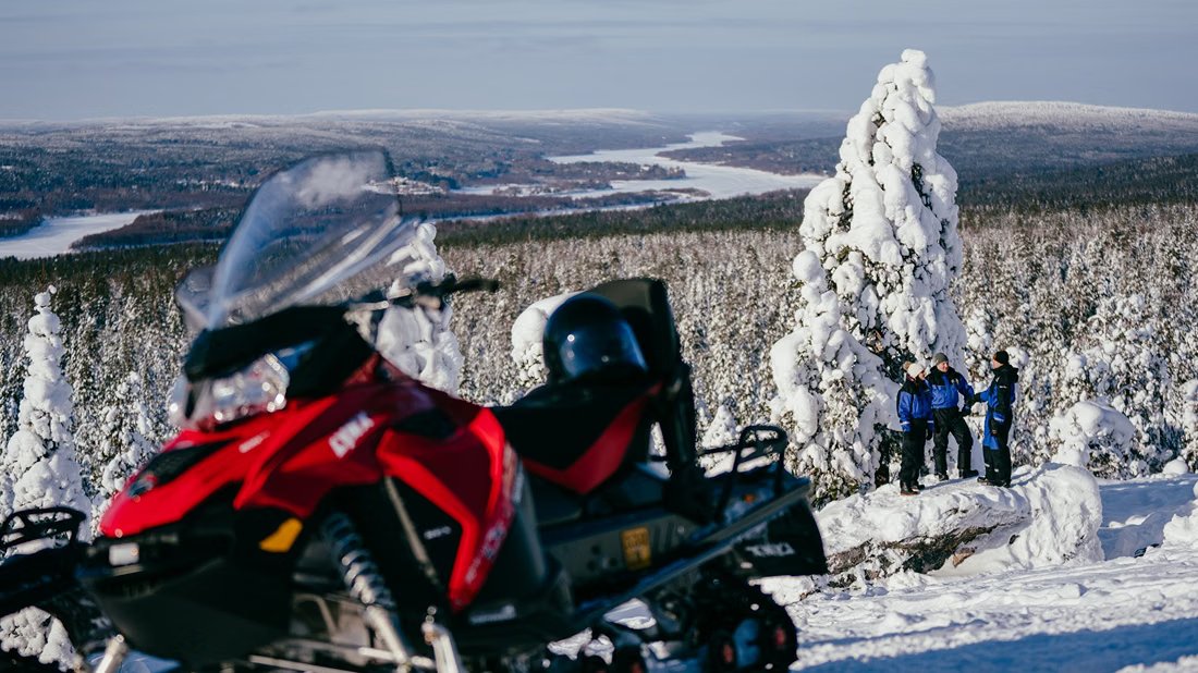 Moto de nieve en la cima de un monte sobre el bosque de Laponia