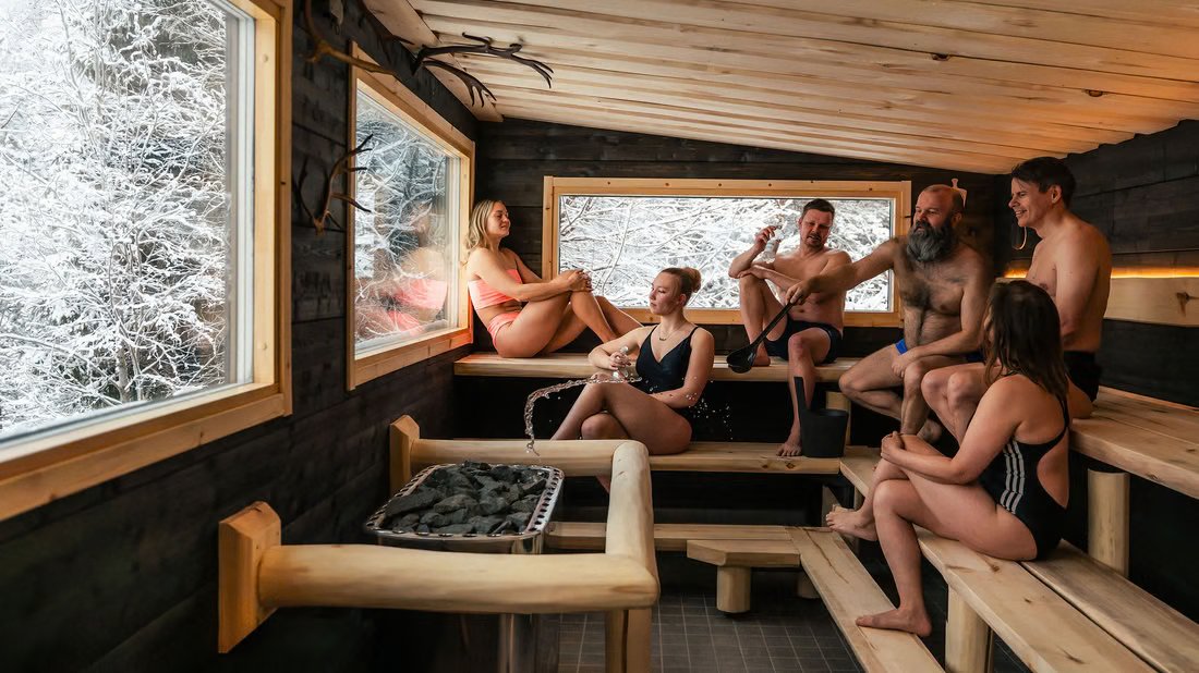 Visitantes relajándose en una sauna revestida de madera