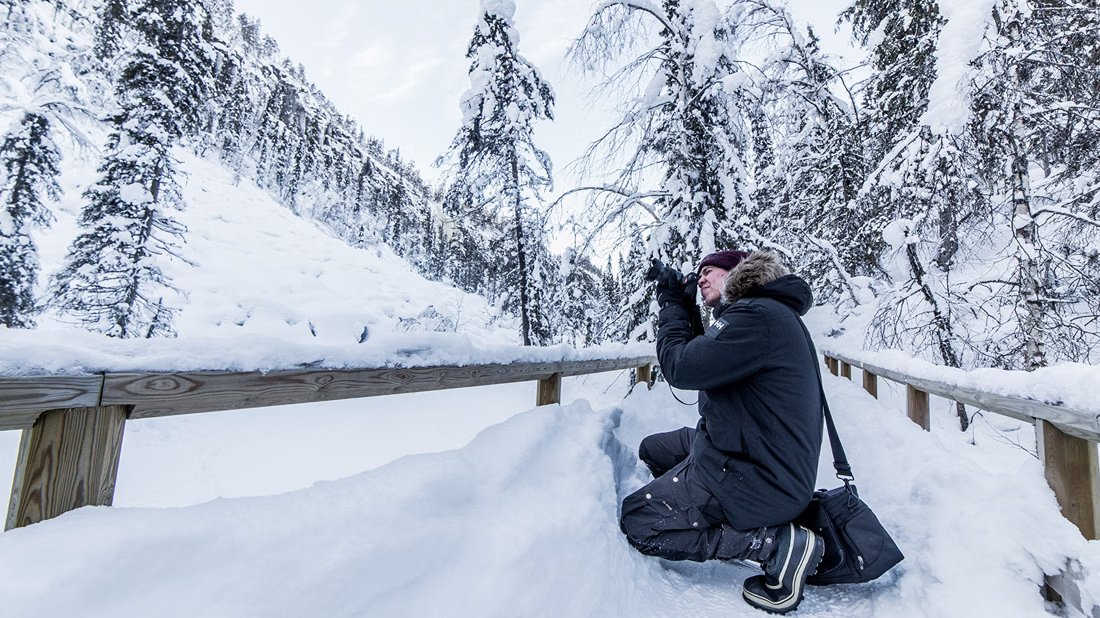 Fotograf auf einem verschneiten Holzsteg