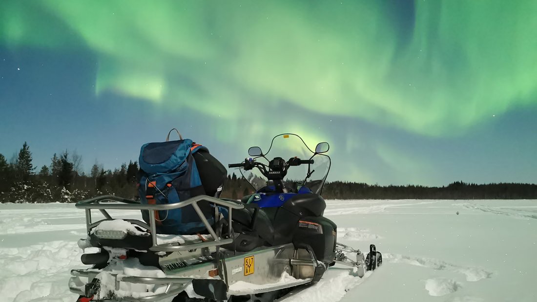 Schneemobil auf einem zugefrorenen See unter den Polarlichtern