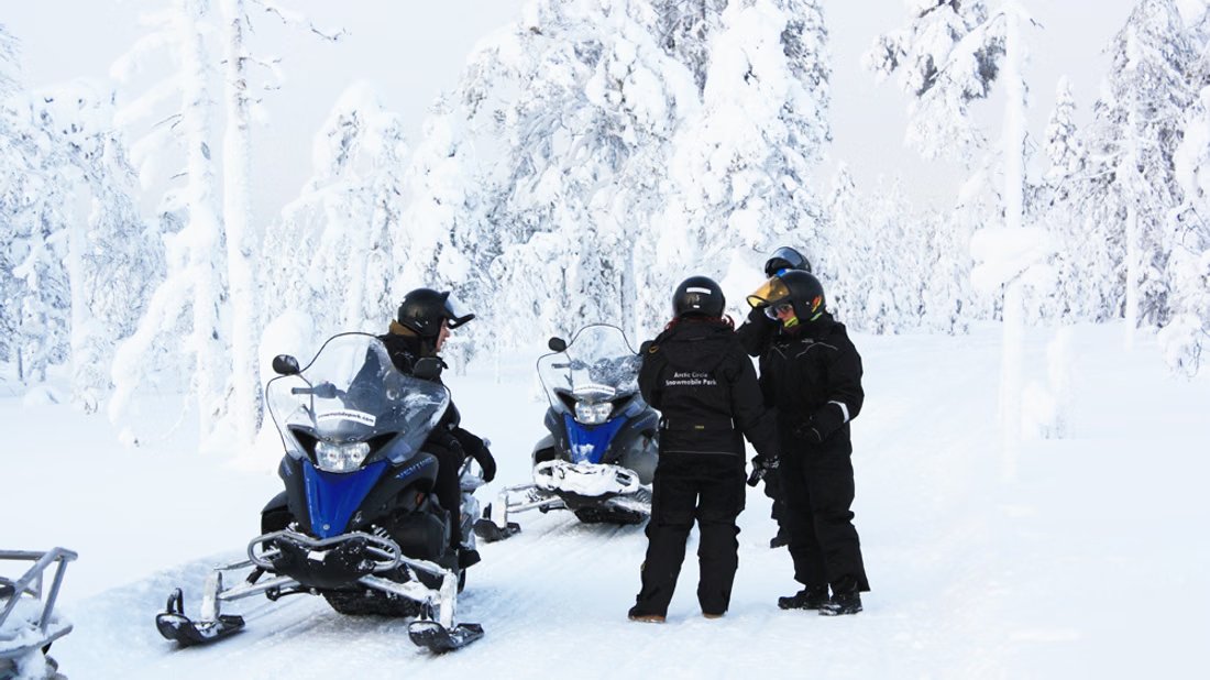 Familia con motos de nieve en un bosque nevado