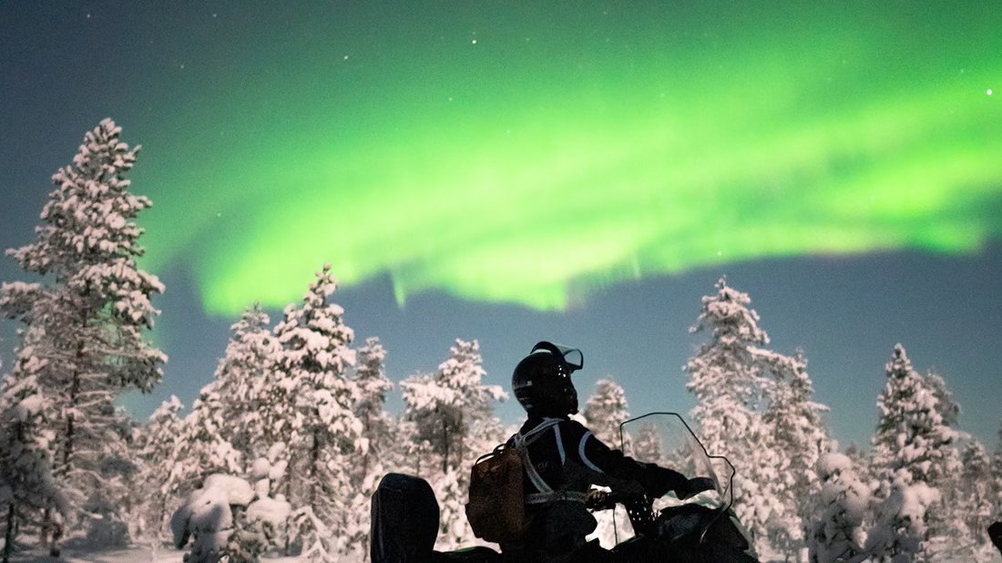 Conductores de motos de nieve bajo las auroras boreales