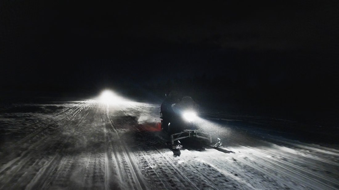 Schneemobilscheinwerfer in der arktischen Nacht